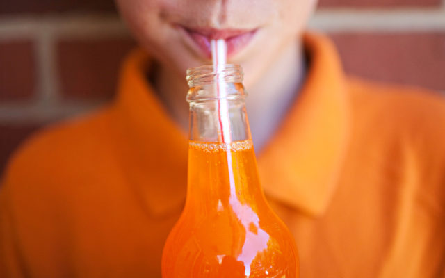 boy drinking orange soda out fo a straw